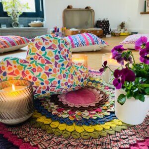 Ambiance chaleureuse et cocooning d’un atelier : tapis moelleux, bougie, coussin nuage et fleurs